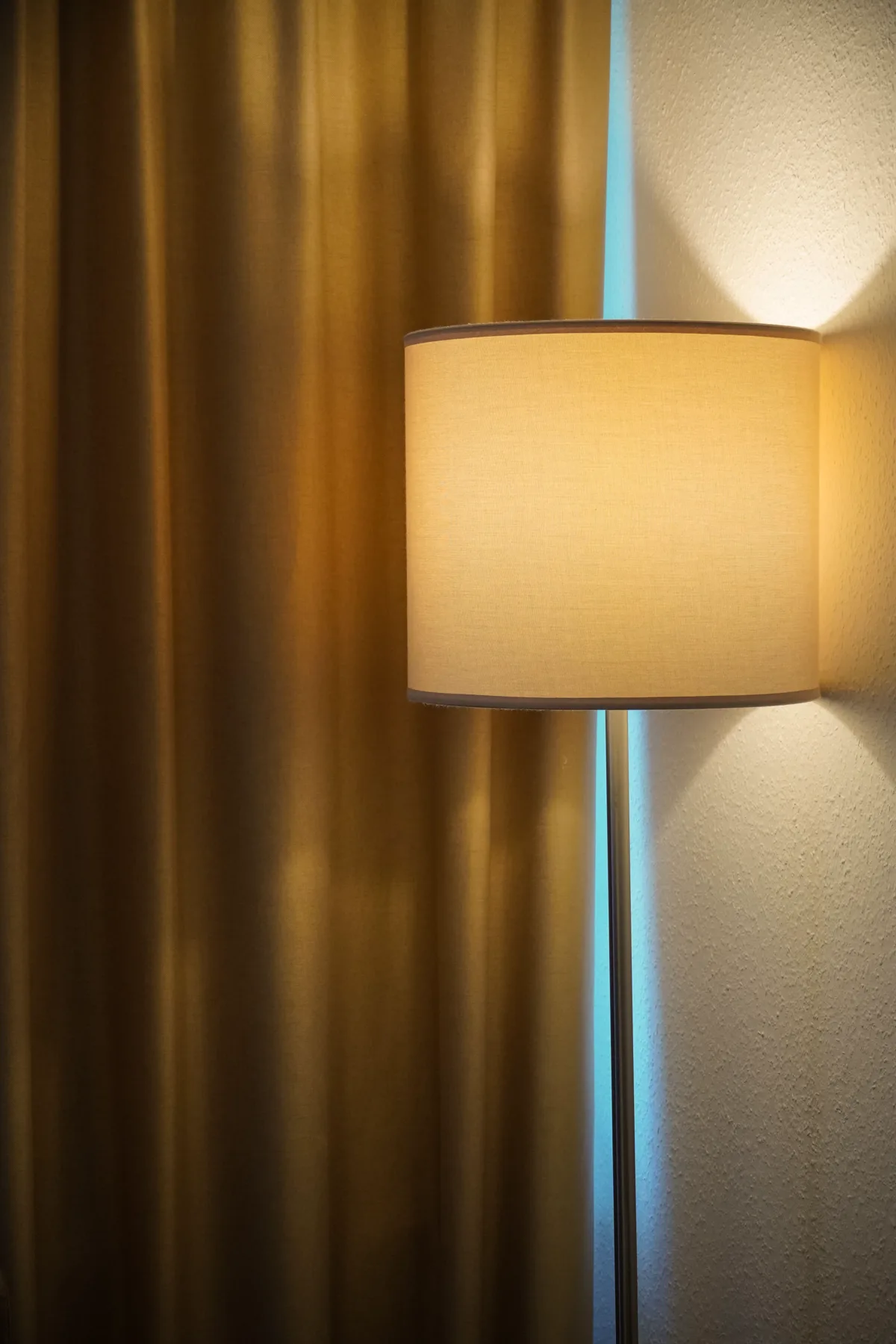 Rideau doré aux plis profonds éclairé par un lampadaire, lumière chaude du soir